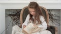 Cute little girl sitting in a Christmas chair and going through a book