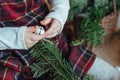 Cute little girl is sitting by the Christmas tree on the floor in the room. Near the baby is a gingerbread house and a basket with