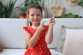 Cute little girl sitting on cozy sofa and pointing up on something intresting by fingers Royalty Free Stock Photo