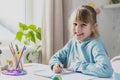 Cute little girl sitting at desk in bedroom, doing homework, studying at home Royalty Free Stock Photo