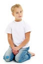 A little girl is sitting on the floor in a clean white T-shirt. Royalty Free Stock Photo