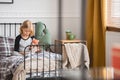 Little girl sitting on her single metal bed in trendy bedroom interior for child