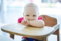 Cute little girl sitting in high chair and smiling Royalty Free Stock Photo
