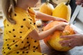 Cute little girl sitting on kitchen table, helping her father to carve large pumpkin. Halloween family lifestyle.