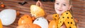 Cute little girl sitting on kitchen table, helping to carve large pumpkin, looking at camera and smiling.