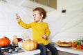 Cute little girl sitting on kitchen table and holding halloween dacorations spider Royalty Free Stock Photo
