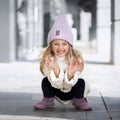 Cute little girl sitting and laughs in knitted hat