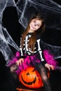 Cute little girl sitting on the pumpkin on black background