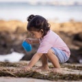 Cute little girl sitting on sandy beach, playing with bucket and sand. Happy childhood. Summer vacation. Holiday concept. Baby Royalty Free Stock Photo