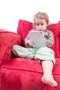 Cute little girl sitting on a sofa with a tablet Royalty Free Stock Photo