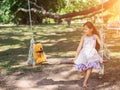 Cute little girl sitting swings , teddy bear sitting with her,little girl pointed to the tree Royalty Free Stock Photo