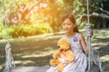 Cute little girl sitting swings , teddy bear sitting with her,little girl pointed to the tree Royalty Free Stock Photo