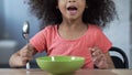 Cute little girl sitting at table with spoon and asking for dinner, hungry kid Royalty Free Stock Photo