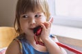 A cute little girl is sitting at a table and talking on an old red home landline phone. Communication, the concept of relationship Royalty Free Stock Photo