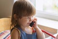 Cute little girl sitting at the table and talking on an old red home phone. Communication, the concept of relationships. European Royalty Free Stock Photo