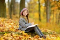 Cute little girl sketching outside on beautiful autumn day. Happy child playing in autumn park. Kid drawing with colourful pencils Royalty Free Stock Photo