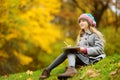 Cute little girl sketching outside on beautiful autumn day. Happy child playing in autumn park. Kid drawing with colourful pencils Royalty Free Stock Photo