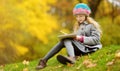 Cute little girl sketching outside on beautiful autumn day. Happy child playing in autumn park. Kid drawing with colourful pencils Royalty Free Stock Photo