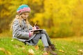 Cute little girl sketching outside on beautiful autumn day. Happy child playing in autumn park. Kid drawing with colourful pencils Royalty Free Stock Photo