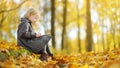 Cute little girl sketching outside on beautiful autumn day. Happy child playing in autumn park. Kid drawing with colourful pencils Royalty Free Stock Photo