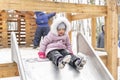 Cute little girl slide down the slide on a winter walk Royalty Free Stock Photo