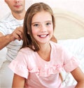 Little girl is smiling while her father is combing daughter`s hair Royalty Free Stock Photo