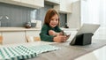 A cute little girl is smiling and watching cartoons on a tablet while eating her breakfast with cereal balls and milk Royalty Free Stock Photo