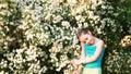 Cute little girl sniffing flowers and playing in the park in summer day.