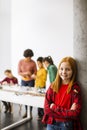 Cute little girl standing in front of kids programming electric toys and robots at robotics classroom