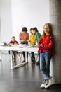 Cute little girl standing in front of kids programming electric toys and robots at robotics classroom