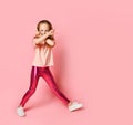 Cute little girl standing with legs wide apart and hiding her face behind two crossed hands. Royalty Free Stock Photo