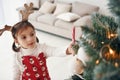 Cute little girl standing new New year tree with candy in hand Royalty Free Stock Photo