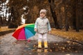Cute little girl standing in puddle near colorful umbrella outdoors Royalty Free Stock Photo