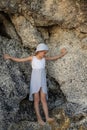 Cute little girl standing between the rocks. Caucasian girl wearing dress and hat. Happy childhood. Summer concept. Traveling with Royalty Free Stock Photo