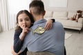 Cute little girl sticking paper fish to father`s back at home