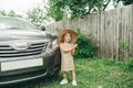 Cute little girl in straw hat standing near car in village Royalty Free Stock Photo