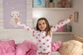 Cute little girl stretching near bed at home Royalty Free Stock Photo