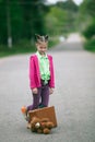 Cute little girl with a suitcase and a stuffed animal standing on the road. Royalty Free Stock Photo