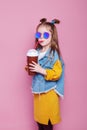 Cute little girl in sunglasses with glass jar of cocktail chilling on pink background Royalty Free Stock Photo