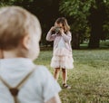 Cute little girl taking a phto of her younger brother