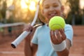 Cute little girl with tennis racket outdoors, focus on ball Royalty Free Stock Photo