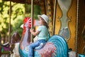 Toddler kid riding vintage roundabout carousel.