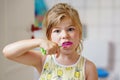 Cute little girl with a toothbrush and toothpaste in her hands cleans her teeth and smiles. Happy preschool child Royalty Free Stock Photo