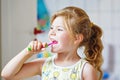 Cute little girl with a toothbrush and toothpaste in her hands cleans her teeth and smiles. Happy preschool child Royalty Free Stock Photo