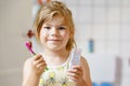 Cute little girl with a toothbrush and toothpaste in her hands cleans her teeth and smiles. Happy preschool child Royalty Free Stock Photo