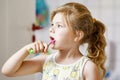 Cute little girl with a toothbrush and toothpaste in her hands cleans her teeth and smiles. Happy preschool child Royalty Free Stock Photo