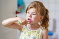 Cute little girl with a toothbrush and toothpaste in her hands cleans her teeth and smiles. Happy preschool child Royalty Free Stock Photo