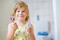 Cute little girl with a toothbrush and toothpaste in her hands cleans her teeth and smiles. Happy preschool child Royalty Free Stock Photo