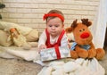 Cute little girl and toy deer under the Christmas tree. Baby holding a gift in her hands Royalty Free Stock Photo