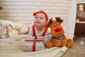 Cute little girl and toy deer under the Christmas tree. Baby holding a gift in her hands and smiling Royalty Free Stock Photo